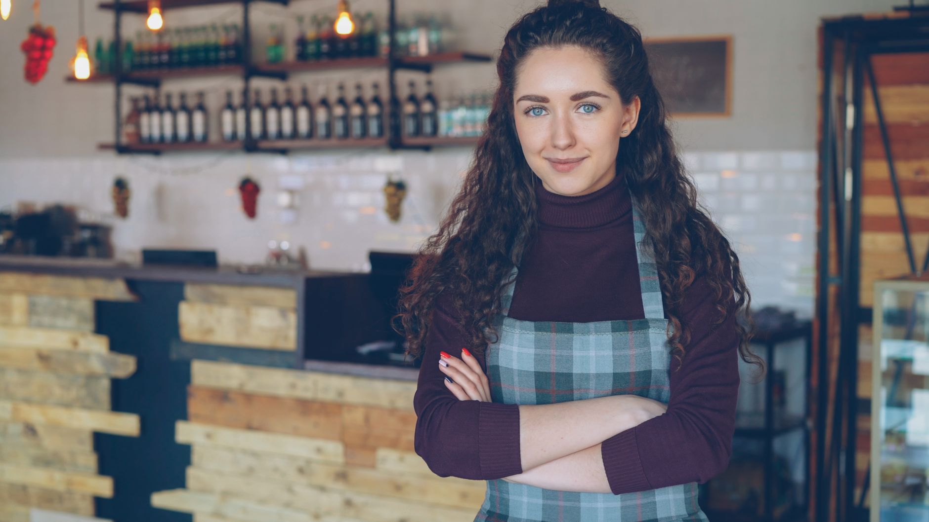 A cafe owner standing with her arms folded inside her own shop