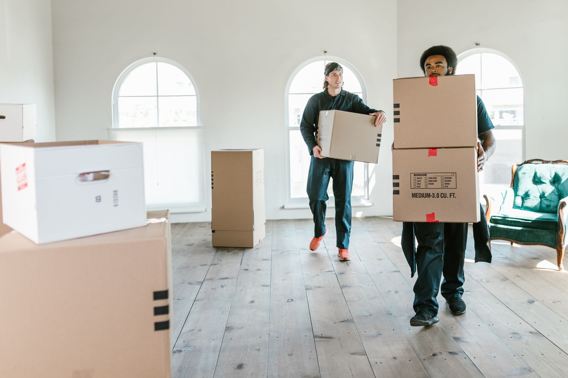 Two movers carrying boxes through a sunlit room